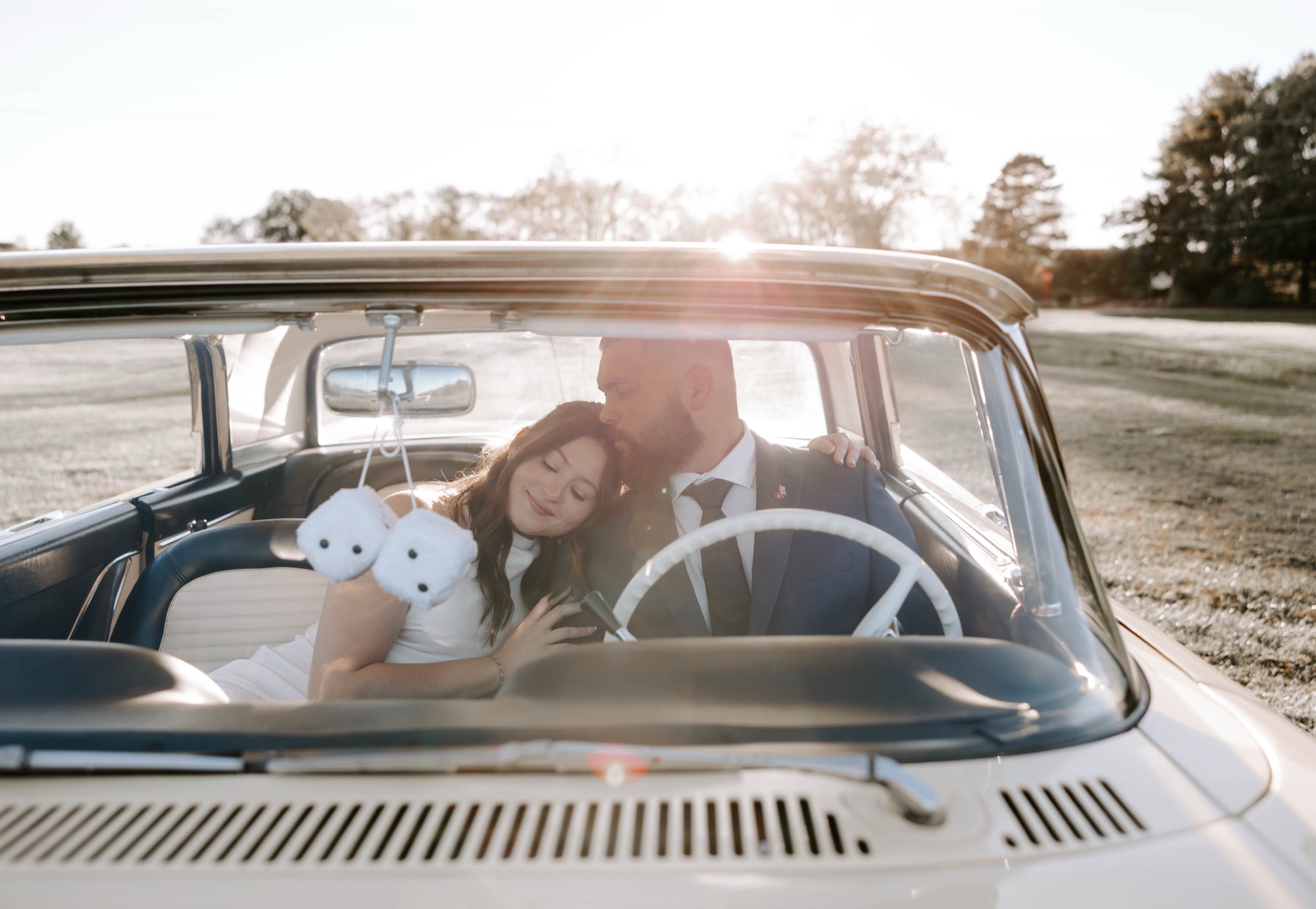 Creative save-the-date photo with couple posing beside vintage ca